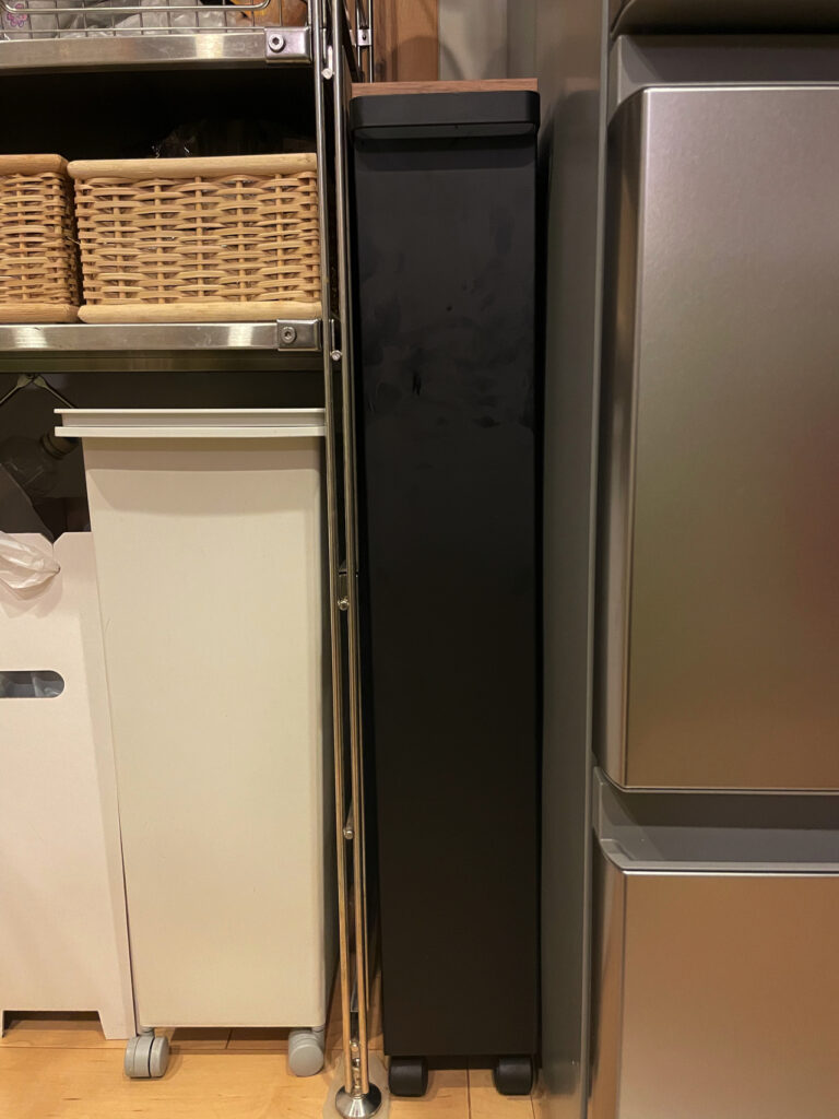 キッチンの棚と冷蔵庫の間に、おしゃれな黒い収納ラックを設置した図